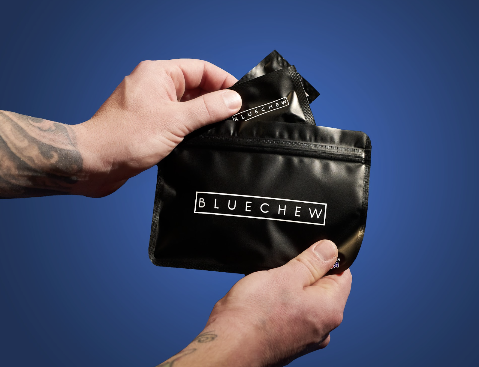 A mans hand holding a bluechew pouch labeled 'BLUECHEW' taking out smaller bluechew pouches visible inside against a blue background.