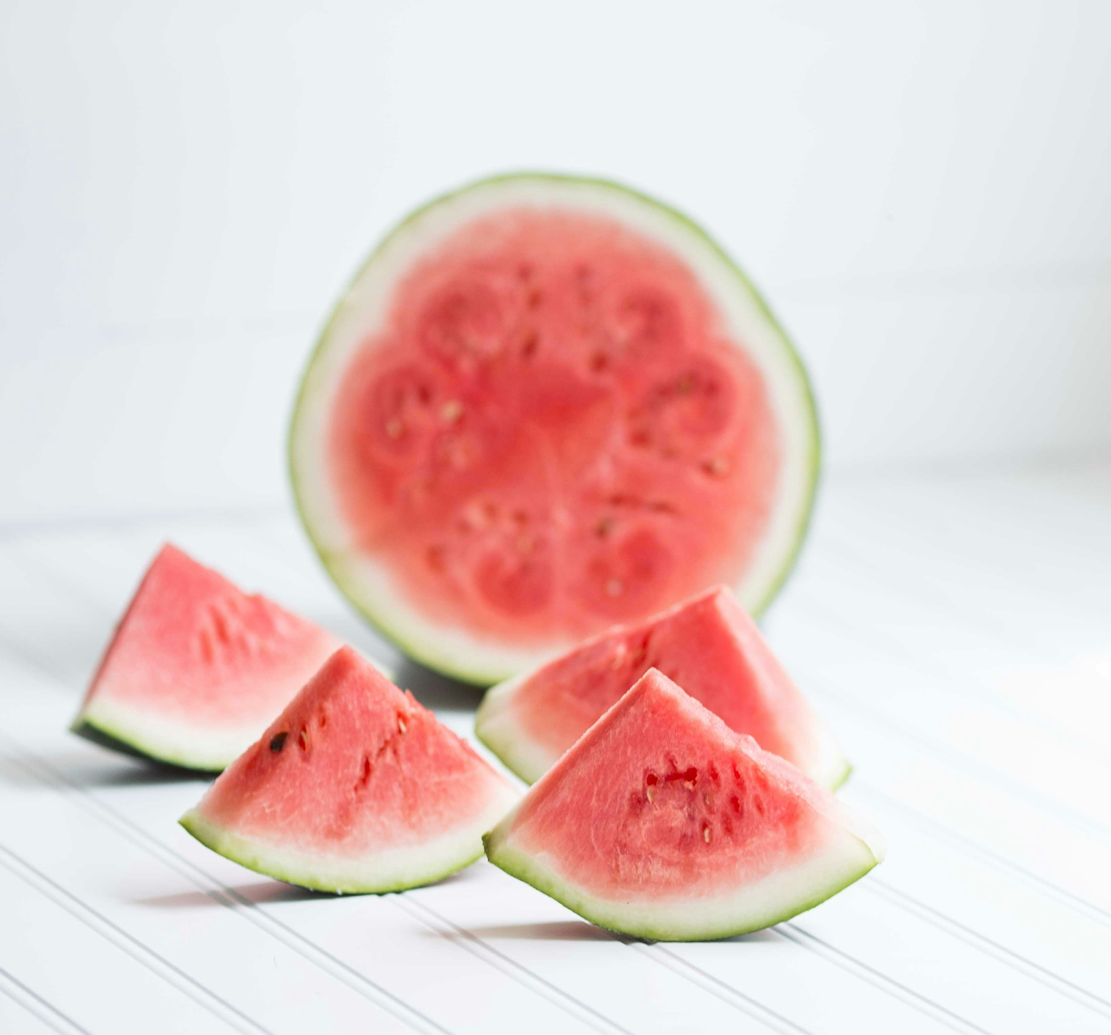 Fresh watermelon slices arranged in a playful manner with a whole watermelon in the background, showcasing the fruit's ability to improve sexual health