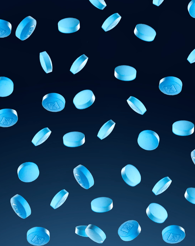 A collection of bluechew blue tablets falling against a dark background, representing erectile dysfunction medication.
