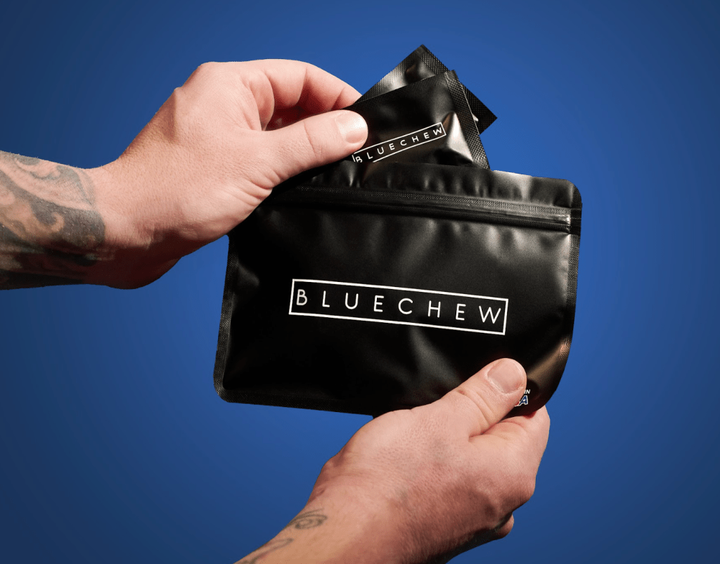 A person's hand holding a Black pouch labeled 'BLUECHEW' with a blue background.