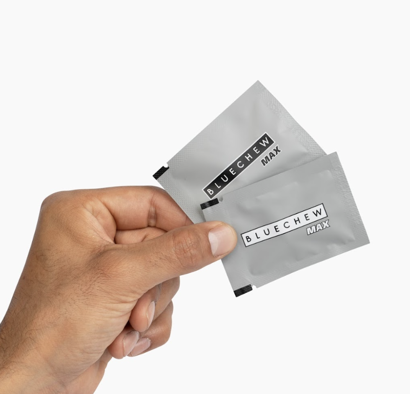 mans hand holind two packets of BlueChew max combo erectile dysfunction medications containing a short-acting and long-acting PDE5 inhibitor