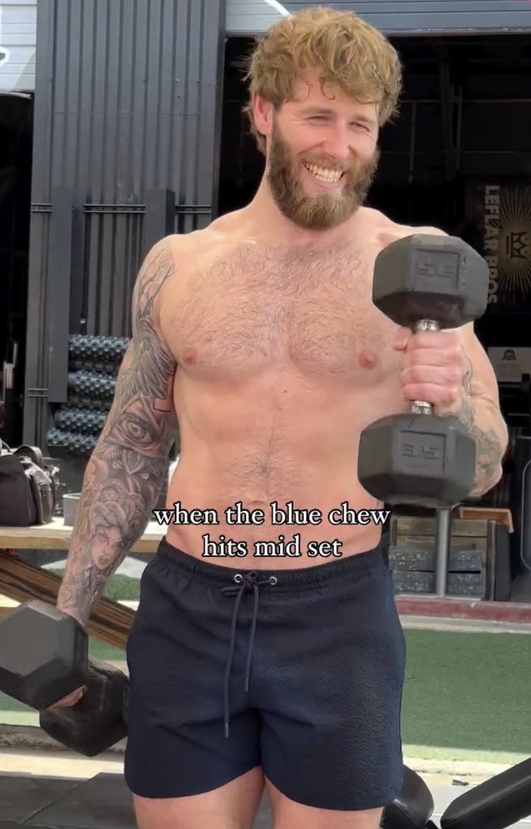 Fit man lifting dumbbells mid-set with a smile, overlaid text: ‘when the blue chew hits mid set.'